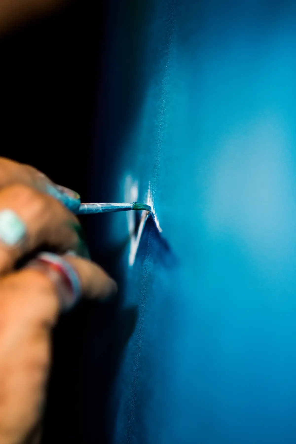 Le pinceau de l’artiste au contact d’une toile bleue